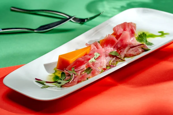 Soğanlı ton balıklı tataki ve balkabağı beyaz tabakta, parlak arkaplanlı. Japon mutfağı. Seçici odak, sert gölgeler