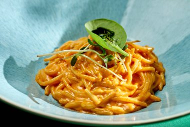 Parlak arkaplanlı bir tabakta domates ve peynir soslu İtalyan spagetti makarnası. Seçici odak, sert gölgeler