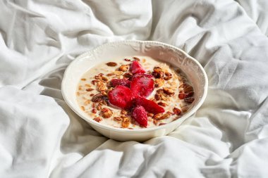 Çilekli yulaf ezmesi ve bir tepside granola. Sert ışık.