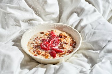Çilekli yulaf ezmesi ve bir tepside granola. Sert ışık.