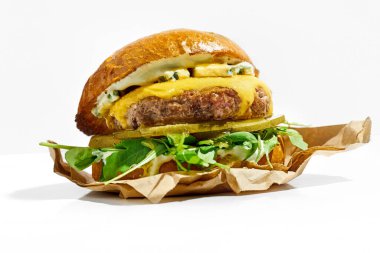 Beyaz arka planda peynirli sulu burger ve roka. Sert Işık