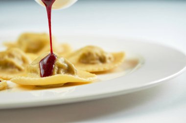 Beyaz bir tabakta Ravioli sosu malzemelerin bileşimine dök. Şefin tabağını süslüyorsun.