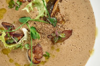 Beyaz masa örtüsünde mantar kremalı çorba.