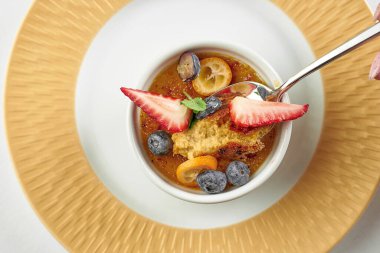 Beyaz masa örtüsü üzerinde krem karamel tabağı. Yakın plan.