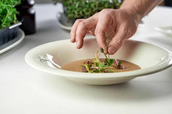 蘑菇奶油汤装饰的过程 厨师把香料和蘑菇放在盘子里 — 图库照片