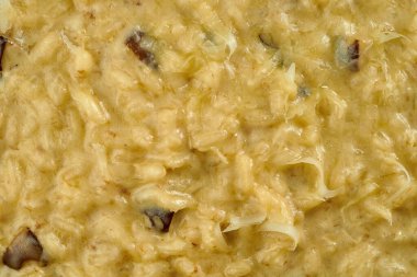 Beyaz masa örtüsü üzerinde beyaz bir tabakta mantarlı risotto dokusu.