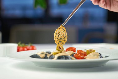 Şef tabakta bir tabak ravioli süslüyor. Seçici odak, yüzeysel alan derinliği