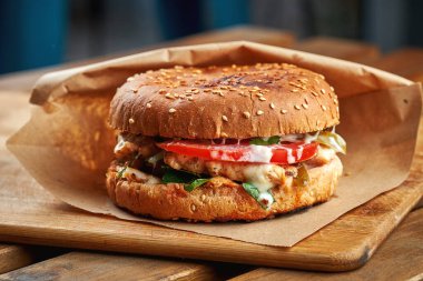 Tahta arka planda kraft kağıdında sebzeli sulu hamburger.