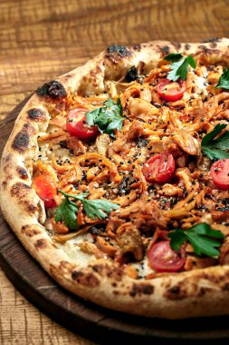 Ahşap zemin üzerinde domatesli et pizzası, kırmızı sos ve susam tohumları. Seçici odak