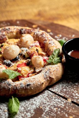 Ahşap arka planda tahta bir tahtanın üzerinde meyveli ve dondurmalı küçük pizza. Seçici odak