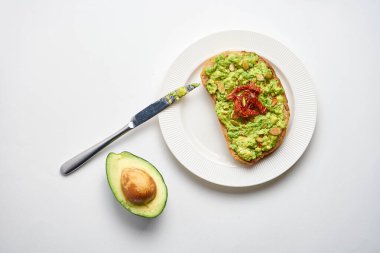 Avokado tostu tabakta, bıçakla ve dilimlenmiş avokadoyla.