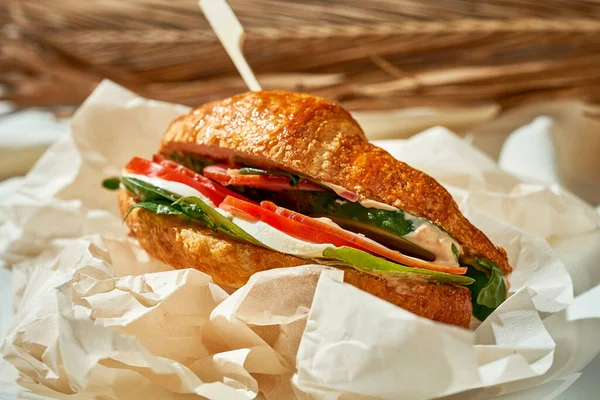 Jambonlu, ıspanaklı ve domatesli kruvasan sandviç. Sert Işık. Beyaz masa örtüsü.