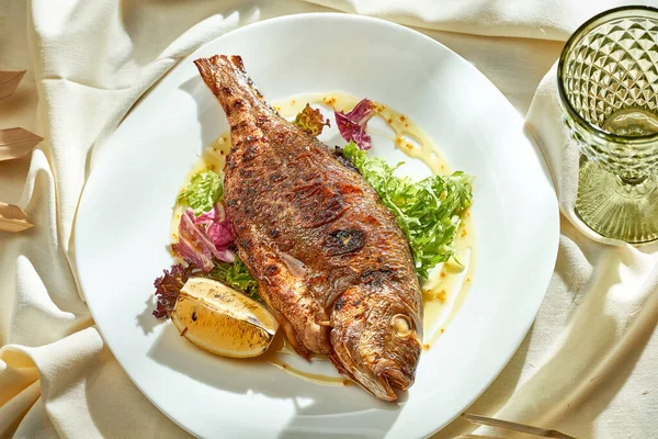 Salatalı fırında dorado ve beyaz tabakta sos. Sert ışık. Seçici odak.