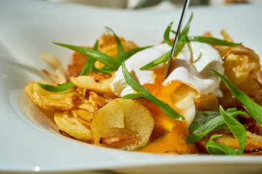 Beyaz bir masa örtüsünde haşlanmış yumurtalı kızarmış patates..