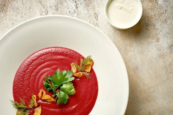 Cream soup of beet with smoked garlic in a bowl. Close-up. Selective focus. Noise added in post-production