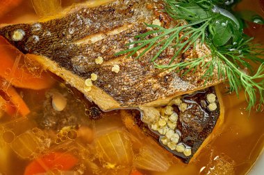 Fish soup with sea bass fillets in a white plate. Close-up, selective focus