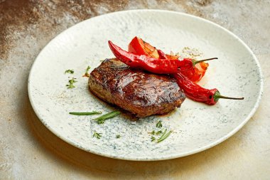 Medium rare steak on a white plate with spices. Close-up, selective focus.