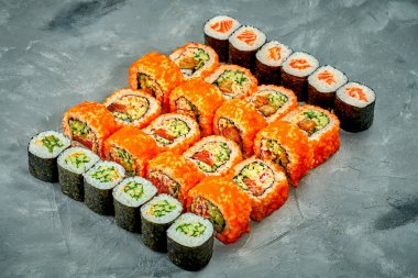 Set of sushi rolls and maki rolls with different fillings on a gray background. Selective Focus