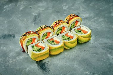 Sushi roll with avocado, salmon, cucumber and Philadelphia cheese on a gray background. Selective focus, noise added in post-production