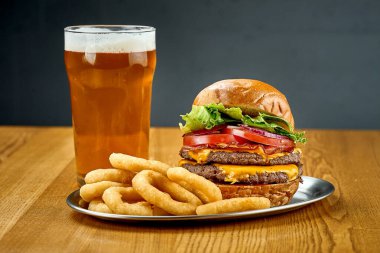 Sebzeli, sulu bir burger ve bir bardak bira. Yakın çekim, seçici odaklanma