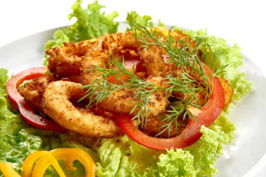 Kızarmış kalamar halkaları beyaz arka planda bir tabakta. Yakın plan. Seçici odak