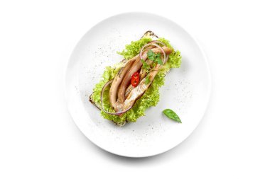 Ringa balıklı sandviç ve beyaz arka planda beyaz bir tabakta sebze. Yakın plan. Seçici odak