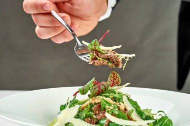 Beyaz tabakta biftek ve parmesanlı salata. Yakın plan. Seçici odak