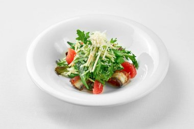 Beyaz arka planda beyaz bir tabakta yılan balığı ve greyfurtlu salata. Yakın çekim, seçici odaklanma