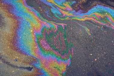 Islak asfalt yüzeyinde bir yağ tabakası. Asfalta petrol ya da benzin dökülmüş.