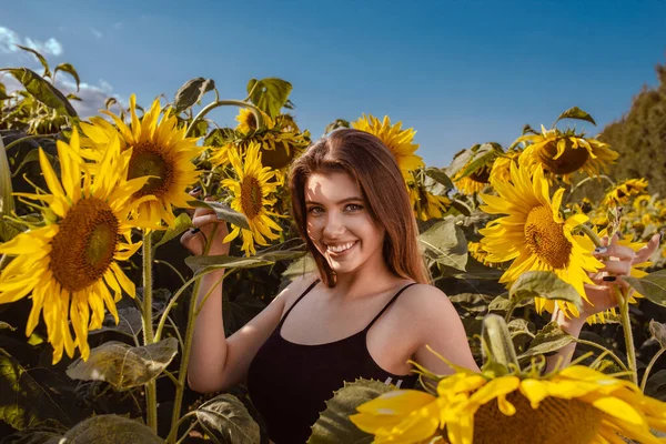 夏の日のひまわり畑で美しい笑顔の若い女性 — ストック写真