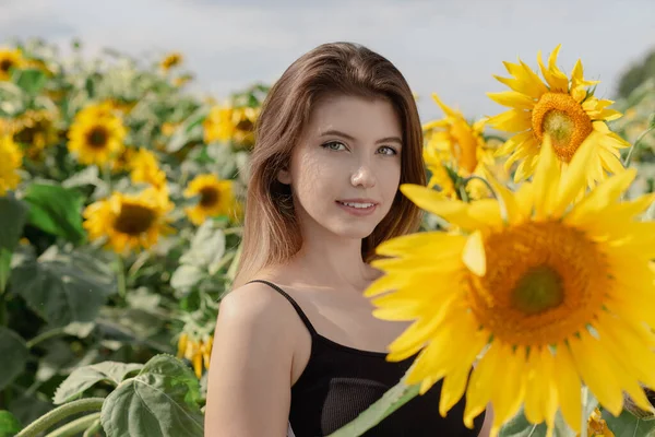 夏の日のひまわり畑の魅力的な笑顔の若い女性 — ストック写真