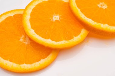 Beyaz bir arka planda üç dilim portakal.