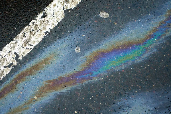 Arka planda yağ sızıntısı ya da beyaz şeritli asfalt bir yolun dokusu. Asfaltta yağ lekesi var.