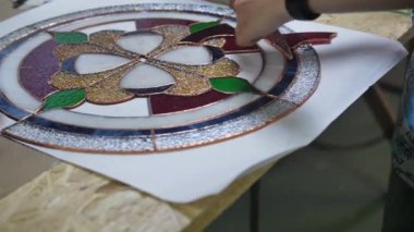 İki sanatçı vitraylı camlardan bir kompozisyon oluşturuyor. Vitrindeki parçaları birleştiriyorum. İki kadının elleri. El yapımı el yapımı. Tiffany boyalı cam. Resmin ayrıntıları.