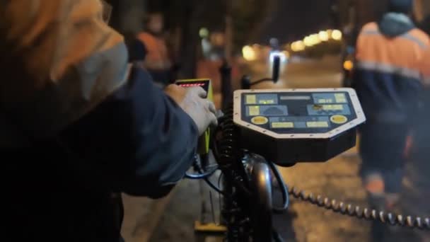 Närbild av en vägarbetare klickar på knapparna på asfaltkontrollpanelen. Reparation av vägar i staden på natten. — Stockvideo