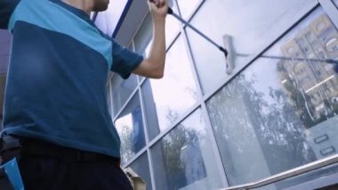 Bir temizlik uzmanının yakın çekim videosu binanın pencerelerini ve cephelerini yıkıyor ve temizliyor.