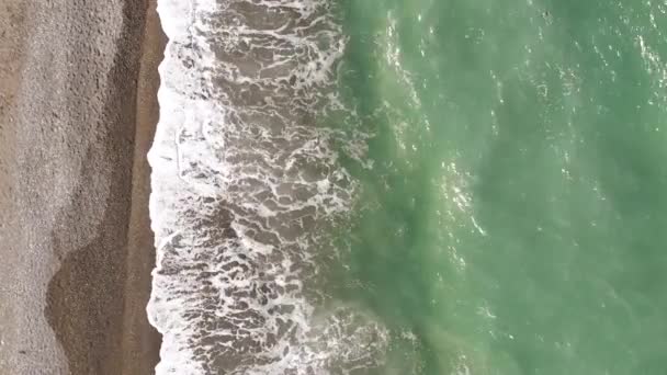 Luchtbeelden van een drone. Vliegen langs de kust. Getijdenboring. Golven rollen over de kust close-up van boven en schuim. — Stockvideo