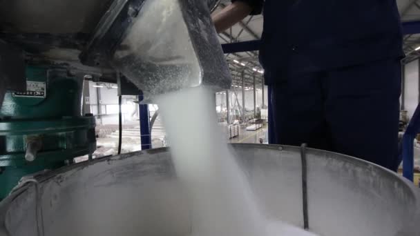 Un travailleur emballe les matières premières en vrac d'un mélangeur automatique dans des fûts et des sacs à l'usine. Fabrication de produits en polypropylène — Video