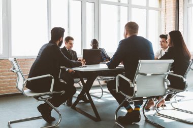 Ofis masasında iş arkadaşlarıyla otururken çalışan ve iletişim kuran bir grup genç iş adamı. iş toplantısı