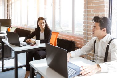 Genç iş adamı modern ofiste bilgisayarla çalışıyor.