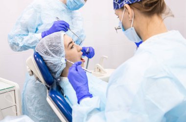 Dişçi konsepti. Profesyonel diş hizmetleri ve acısız modern ekipmanlar. Asistanı olan bir doktor hastaların dişlerini tedavi eder ve anestezi yapar.