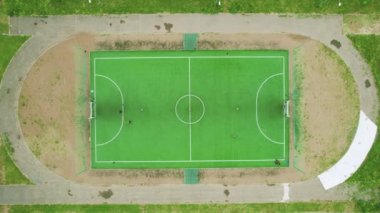 Futbol sahasının yukarıdan görünüşü. Çocuklar taşra bir kasabada futbol oynarlar. Hava aracı 4K görüntüsü