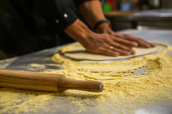 Chef profesional cocinando en el restaurante de cocina del hotel, preparando la cena. Un cocinero en delantal hace una pizza. hombre lanza masa de pizza —  Fotos de Stock