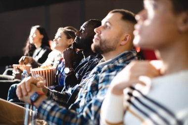 Arkadaşlar sinemada patlamış mısırlı bir film izliyorlar. İnsanlar sinemanın koltuklarında oturur ve ekrana bakarlar.