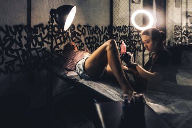 Profesyonel kadın dövme sanatçısı stüdyoda dövme yapıyor, yakın plan. Karanlık fotoğrafçılık