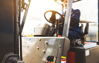 Forklift kullanan bir adam büyük bir depoda çalışır ve bir çanta dolusu hammaddeyi boşaltır.