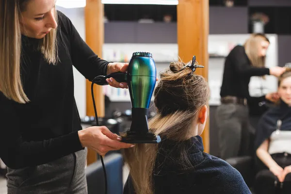 Master γυναίκα κομμωτήριο στεγνώνει τα κορίτσια μαλλιά με στεγνωτήρα μαλλιών μετά το πλύσιμο σε ένα σαλόνι ομορφιάς. — Φωτογραφία Αρχείου