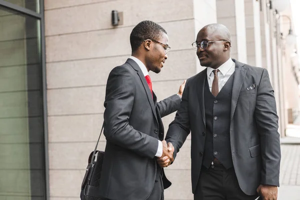 Retrato de dos hombres de negocios afroamericanos negros con trajes que se dan la mano al aire libre. La alegría de conocer buenos amigos — Foto de Stock