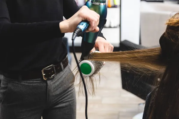 Master žena kadeřnice vysuší dívky vlasy s fénem a hřebeny po mytí v salonu krásy — Stock fotografie