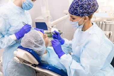 Dişçi konsepti. Profesyonel diş hizmetleri ve acısız modern ekipmanlar. Asistanı olan bir doktor hastaların dişlerini tedavi eder ve anestezi yapar.